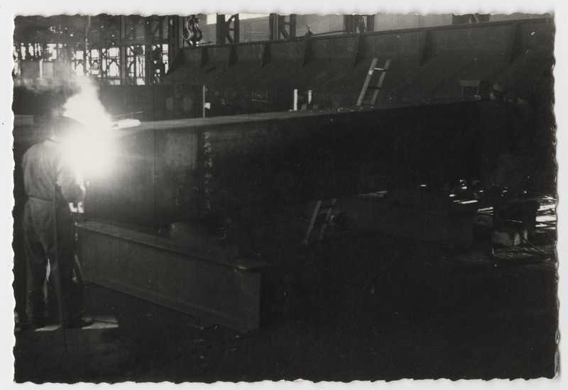 Interno del deposito di elementi prefabbricati per la costruzione di opere di presa. Operaio alla saldatura